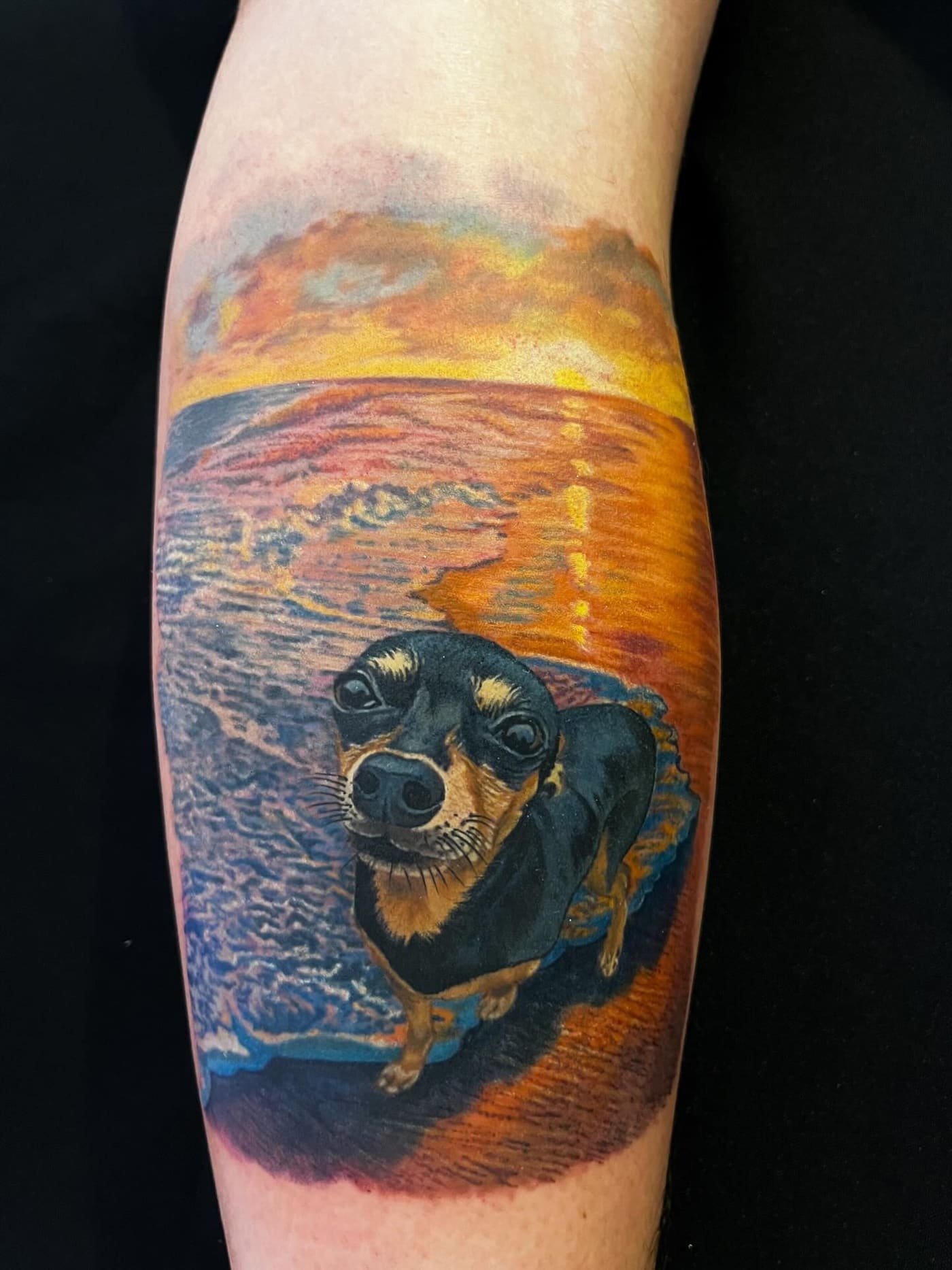 Tatuaggio realistico di un cane su sfondo tramonto in spiaggia